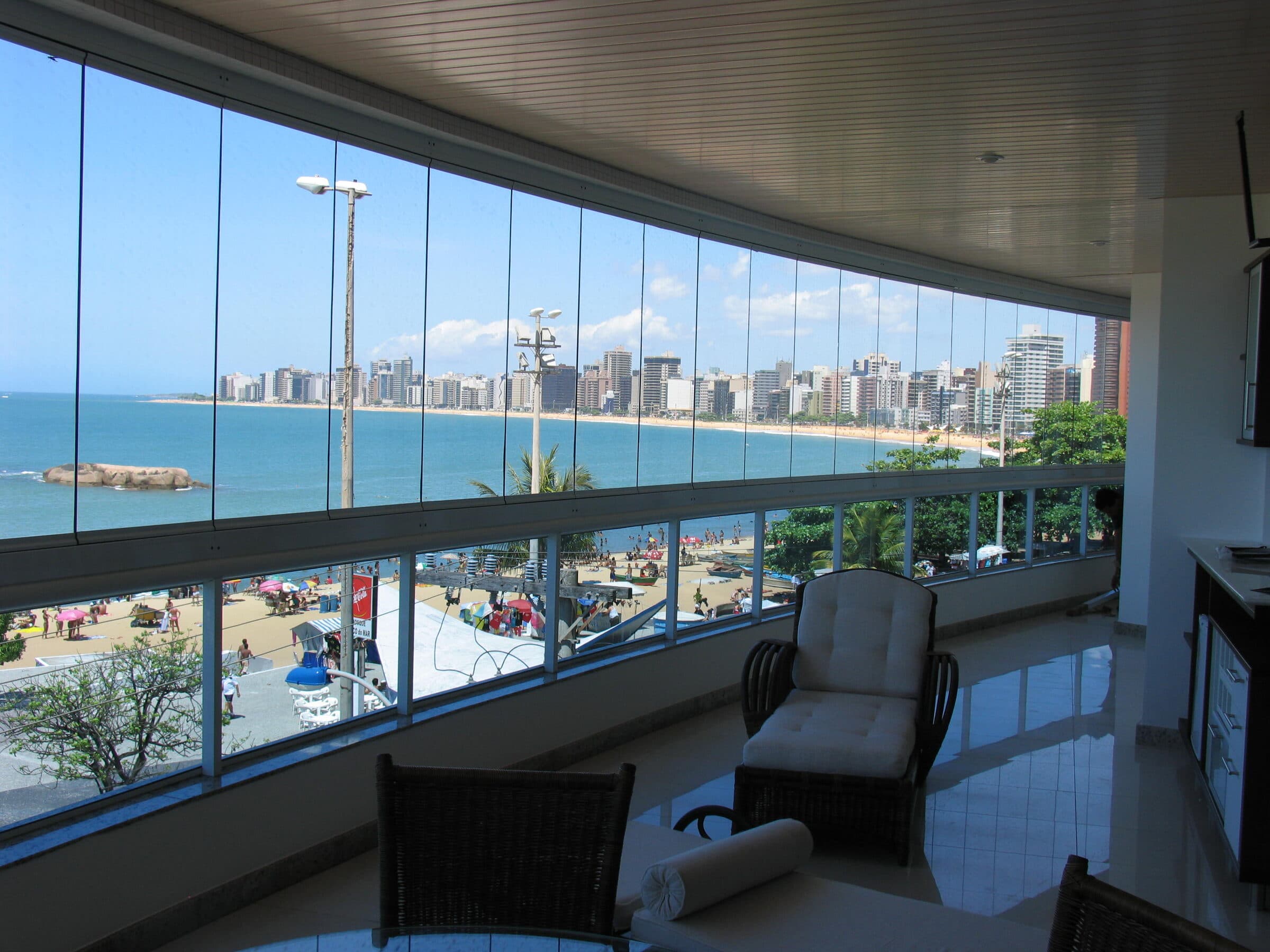 Varanda envidraçada com vista para o mar e mobiliário de descanso